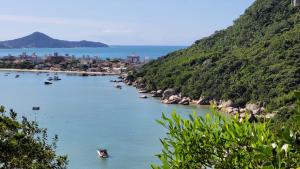 a river with boats in the water next to a mountain at Apto. 2 quartos em Bombinhas (60 m da praia) in Bombinhas
