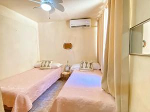 two twin beds in a room with a ceiling fan at Casa ALOA Ixtapa in Ixtapa
