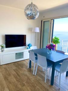ein Esszimmer mit einem blauen Tisch und einem TV in der Unterkunft Blue Jolie in Scilla