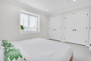 a white bedroom with white cabinets and a large bed at Family-Friendly, 3 Bed House - Private Backyard-Central Location in Vancouver