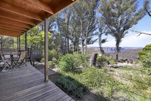 a wooden porch with a table and a view of the canyon at Canyon Cottage Majestic view in Blackheath