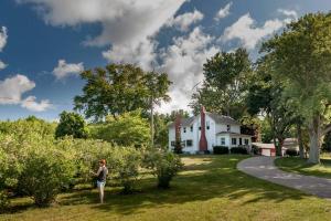 a woman standing in front of a white house at Blue Vieira Cottage in Fennville