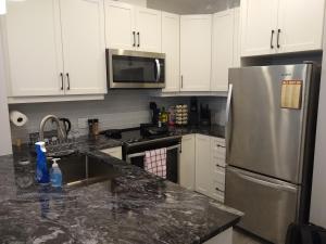 a kitchen with white cabinets and a stainless steel refrigerator at Comfy Condo Near Downtown in Kitchener