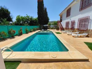 a swimming pool in a yard with chairs and a building at Esmeraldas Vivienda Rural in Villacarrillo