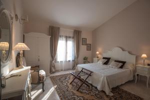 ein Schlafzimmer mit einem Bett, einem Stuhl und einem Tisch in der Unterkunft Il Casale Relais in San Giuliano Terme