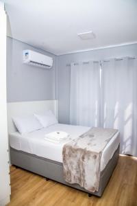 a bedroom with a bed with white sheets at Flat - Mini House in Lagoa Santa