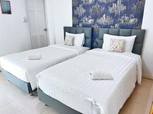 two beds sitting next to each other in a room at Malizon Hotel and Residences in Nonthaburi