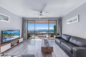 a living room with a couch and a television at OCEAN VIEWS 16 pool & Spa Wi-FI in Airlie Beach