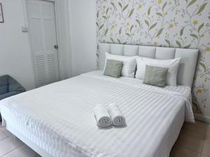a bedroom with a white bed with two towels on it at Malizon Hotel and Residences in Nonthaburi