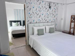 a bedroom with a large white bed with a mirror at Malizon Hotel and Residences in Nonthaburi