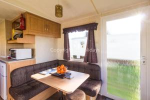 sala de estar con mesa y cocina en Great 6 Berth Caravan For Hire At Sunnydale Holiday Park In Skegness Ref 35150tm en Louth