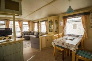 a kitchen and living room with a table and a couch at Superb Caravan With Decking Close To Hunstanton Beach In Norfolk Ref 23060s in Hunstanton