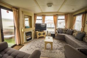 a living room with a couch and a television at Superb Caravan With Decking Close To Hunstanton Beach In Norfolk Ref 23060s in Hunstanton