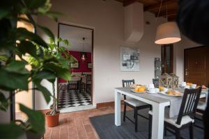 a dining room with a white table and chairs and a kitchen at Il Casale Relais in San Giuliano Terme +14 photos