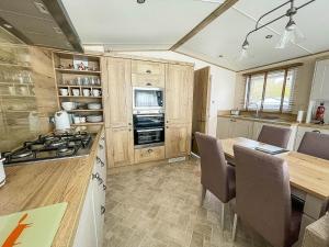 a kitchen with a table and a stove top oven at Modern Caravan With Large Decking Area And Wifi, Ref 60057ch in Saxmundham