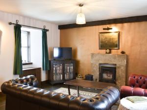 a living room with a leather couch and a fireplace at Primrose Cottage in Elgin