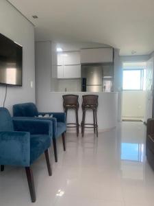 a living room with blue chairs and a kitchen at Apt na Torre - Recife in Recife