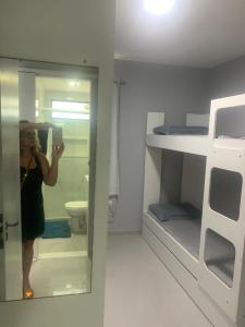 a woman taking a picture of a bathroom with a mirror at Apt na Torre - Recife in Recife