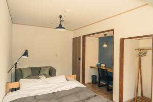 1 dormitorio con cama, silla y escritorio en Raicho Onsen Inn, en Matsumoto