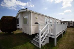 a white tiny house with a staircase in a yard at Lovely 6 Berth Caravan With Decking At Sunnydale Holiday Park Ref 35130sd in Louth