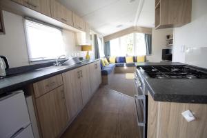 una cocina con fregadero y estufa horno superior en Caravan With Decking Within Walking Distance To Hunstanton Beach Ref 23054S, en Hunstanton