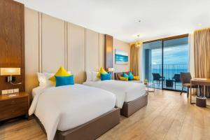 two beds in a hotel room with a view of the ocean at Homie Panorama Beachfront Residences Nha Trang in Nha Trang