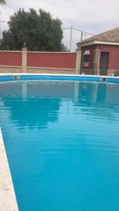 una gran piscina azul frente a una casa en CHALET VACACIONAL a 10 minutos de la playa de La Barrosa, en Chiclana de la Frontera