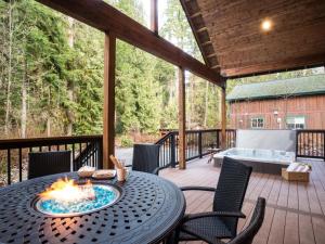 eine Terrasse mit einem Tisch und einer Feuerstelle auf einer Terrasse in der Unterkunft Cottonwood Cabin in Glacier