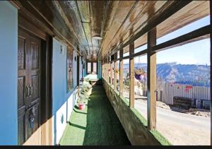 a corridor of a building with windows and green grass at Deodar Homestay Dakbangla-kufri in Shimla