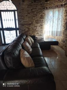 a black leather couch in a room with a brick wall at CHALET VACACIONAL a 10 minutos de la playa de La Barrosa in Chiclana de la Frontera