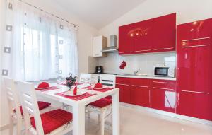 una cocina con armarios rojos y una mesa y sillas blancas. en Lovely Home In Pula With Wifi en Pula