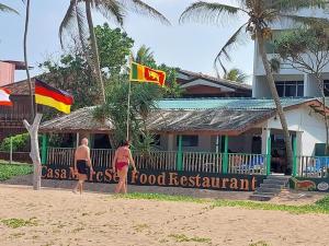 two people walking on the beach next to a food restaurant at New Casamarc in Bentota