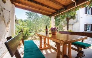 uma mesa de madeira e cadeiras num pátio com uma garrafa de vinho em Lovely Apartment In Krk With Kitchen em Brzac