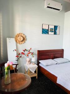 een slaapkamer met een bed en een tafel met bloemen bij Homestay Tiên Tri 02 in Ly Son