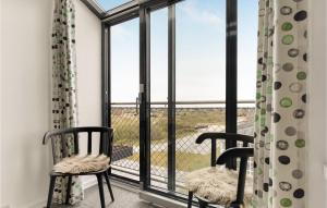 a room with two chairs and a balcony with windows at Fanø Bad, Lejl 65 in Fanø