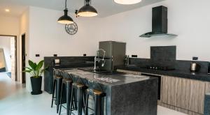 a kitchen with a black counter and bar stools at Ozzy villa phangan in Wok Tum