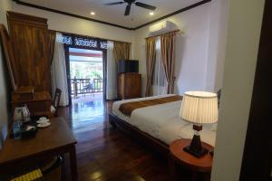 ein Schlafzimmer mit einem Bett und einem Tisch mit einer Lampe in der Unterkunft Lux Hotel in Luang Prabang