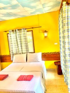 a yellow bedroom with a bed with two red pillows on it at Koh Tao Tropicana Resort in Koh Tao
