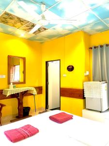 a yellow room with a bed and a mirror at Koh Tao Tropicana Resort in Ko Tao