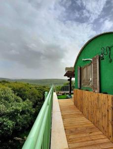 a green building with a wooden walkway leading to it at בקתת מרווה in Abirim +12 photos