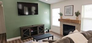 een woonkamer met een open haard en een televisie aan de muur bij Valley Magnolia. Tranquil + Stylish. Near Hospital in Hanford