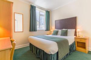 ロンドンにあるロンドン タウン ホテルの大きなベッドと窓が備わるホテルルームです。