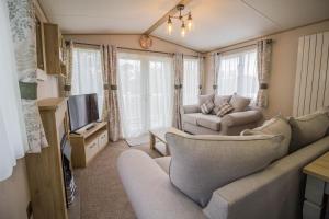 a living room with a couch and a tv at Beautiful 6 Berth Caravan With Decking At Southview Holiday Park Ref 33024o in Skegness