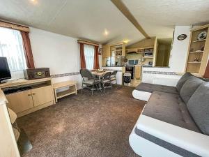sala de estar con sofá y mesa en Caravan At Highfield Grange With Decking, Sleeps 6 Ref 26446ba, en Clacton-on-Sea