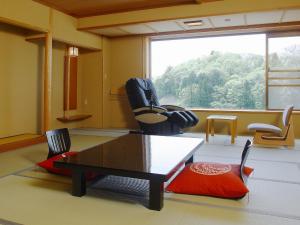 a living room with a table and chairs and a large window at Hotel Oyanagi in Tagami