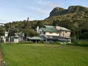a house in a field with a mountain in the background at The Green Savanna Holiday Bungalow Nuwara Eliya in Nuwara Eliya