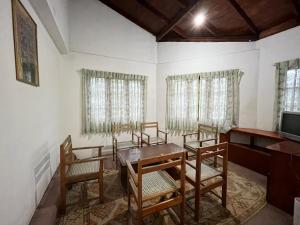 a dining room with chairs and a table and a television at The Green Savanna Holiday Bungalow Nuwara Eliya in Nuwara Eliya