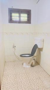 a bathroom with a toilet with a black seat at Elara Beach View HomeStay in Alleppey