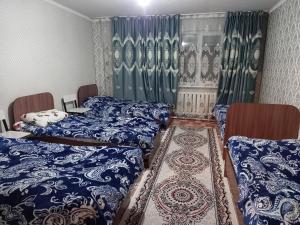 Habitación con 2 camas y sábanas azules y blancas. en Kausar, en Karabulak