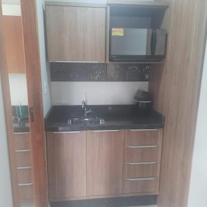 a small kitchen with a sink and a microwave at Bienenwabe Suítes Super Luxo in São Pedro de Alcântara